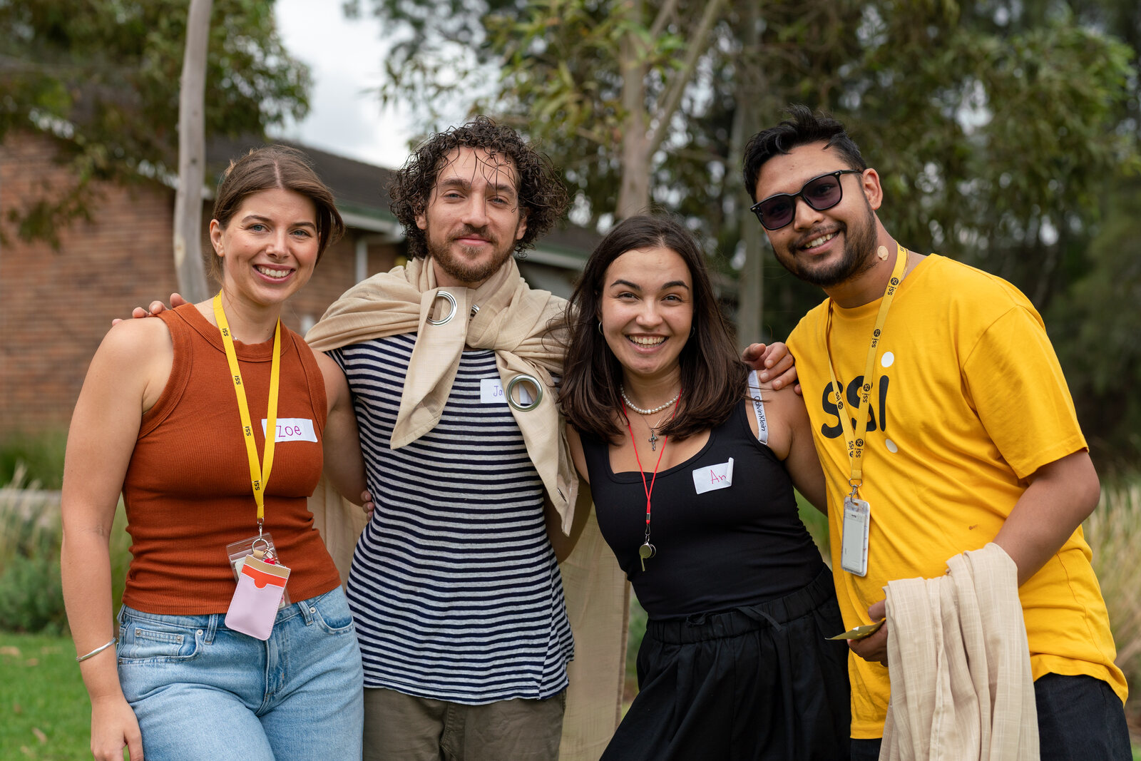 Four smiling SSI team members stand arm in arm outdoors.