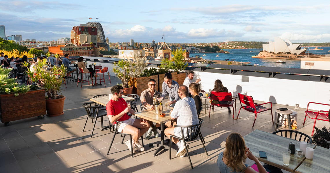 Guests on the rooftop terrace of YHA Sydney Harbour, overlooking the harbour.