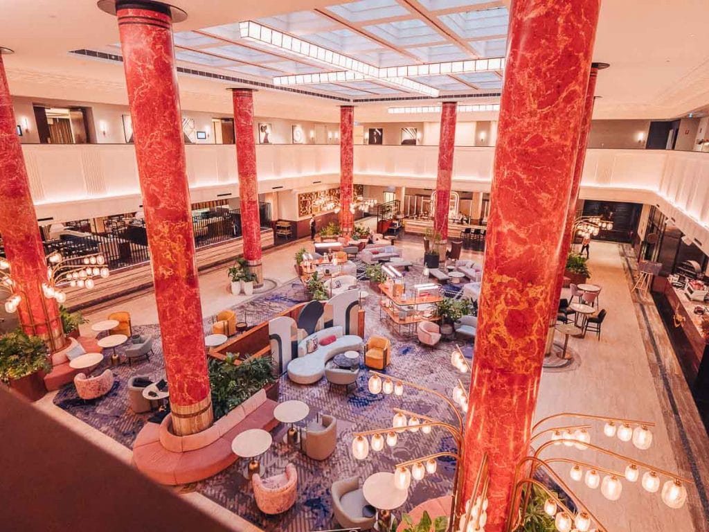 The lobby at Kimpton Margot Sydney, with red marble columns and lounge seating beneath a double-height atrium
